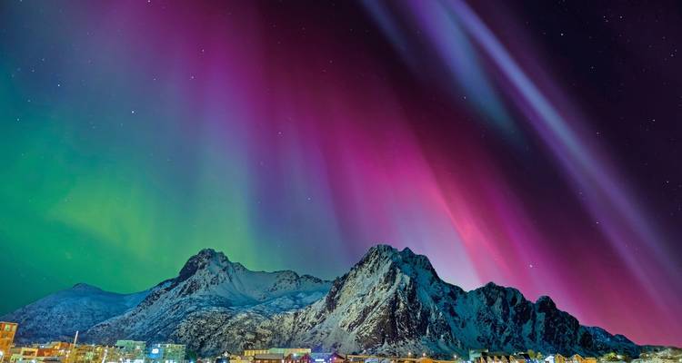 Spectacle spectaculaire d'aurores boréales colorées au-dessus de montagnes enneigées.