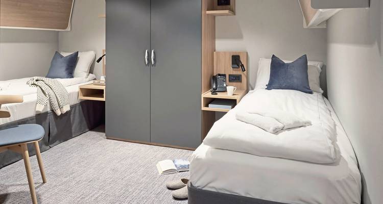 Cabine avec lit simple au décor moderne et équipements.