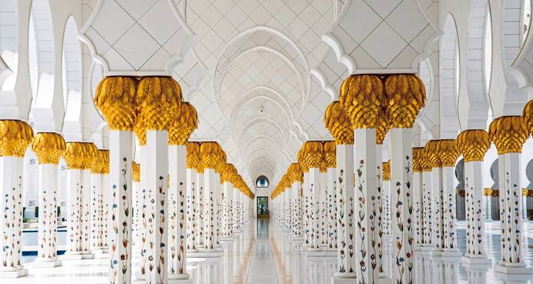 Intérieur d'une mosquée blanche ornée avec des accents dorés.