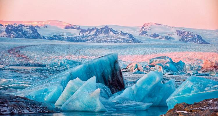 Eisberge in einer gefrorenen Landschaft unter einem rosa Himmel.