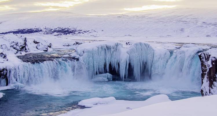 Gefrorener Wasserfall in einer verschneiten Landschaft an einem Wintertag.