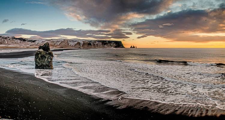 Malerische Aussicht auf den schwarzen Sandstrand Reynisfjara mit dramatischen Wolken.