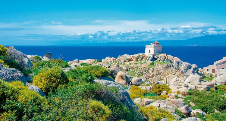 A scenic view of rocky terrain with a small building and blue sea.