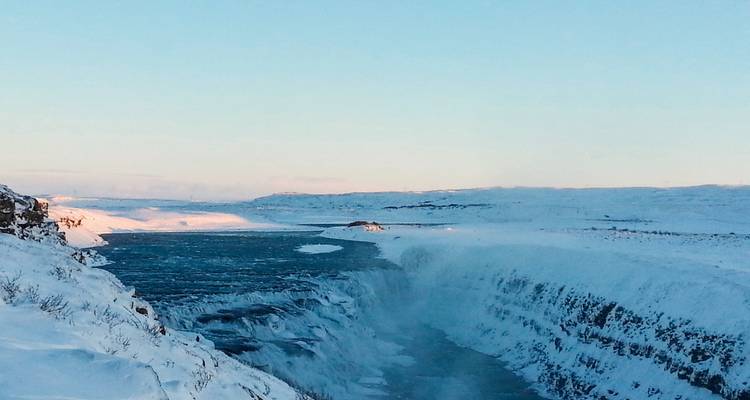 Gefrorener Wasserfall in einer weiten verschneiten Landschaft.