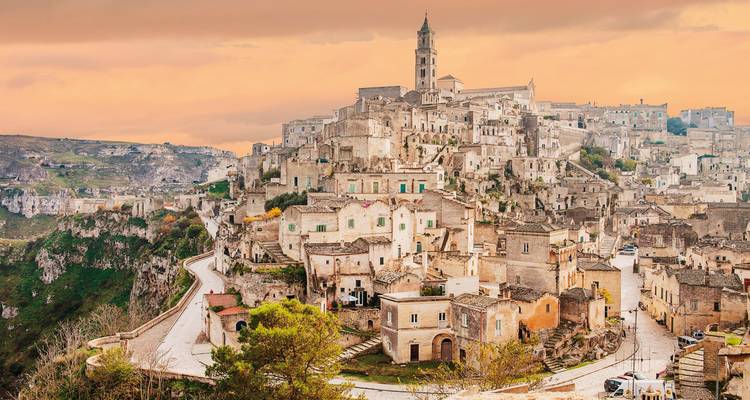 Paysage urbain historique à flanc de colline sous un ciel chaleureux.