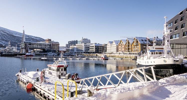 Verschneiter Hafen mit modernen Gebäuden und Booten.