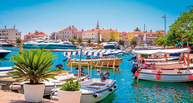 Bateaux colorés dans une marina avec une ville historique et une église en arrière-plan.