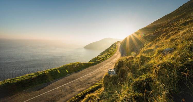 Route côtière avec vue sur la mer au coucher du soleil.