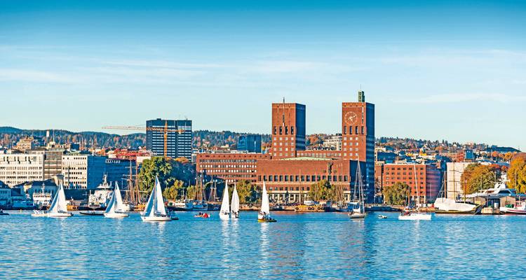 Hafenszene mit Rathaus und Segelbooten an einem sonnigen Tag.