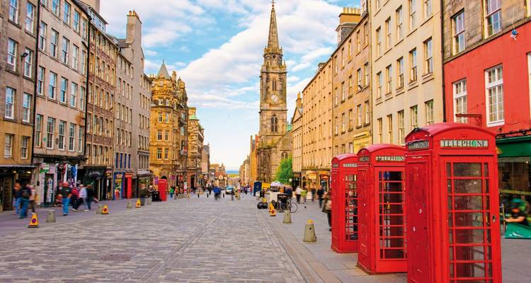 A bustling street in Edinburgh with historic buildings and iconic red phone booths.