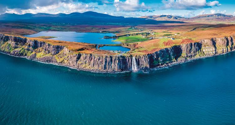 Aerial view of a cliff-lined coast with a vibrant countryside.