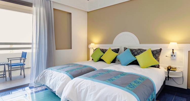 Hotelzimmer mit zwei Einzelbetten und Balkon mit Aussicht.