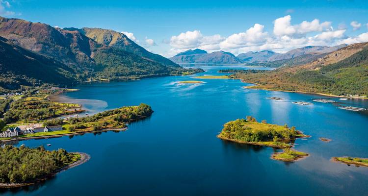 Aerial view of a Scottish loch surrounded by mountains and forests.