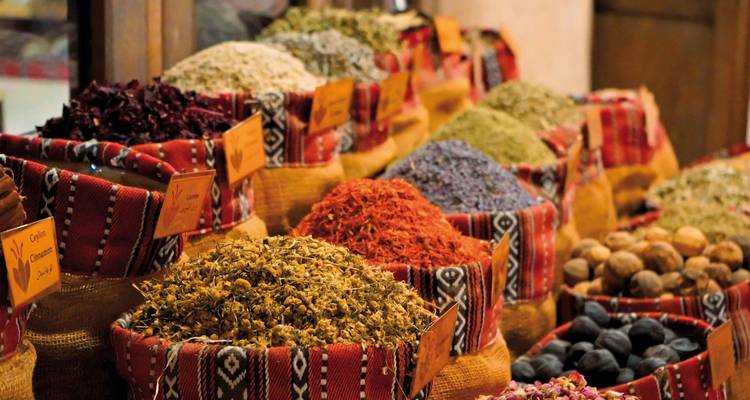 Bunte Gewürze, die in Marktständen mit dekorativen Stoffelementen ausgestellt sind.