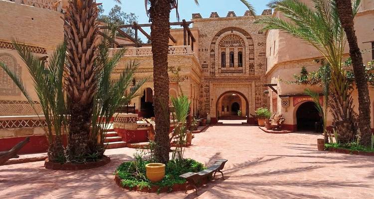 Friedlicher Innenhof einer Adobe-Kasbah geschmückt mit Bögen, Palmen und Terrakotta-Fliesen