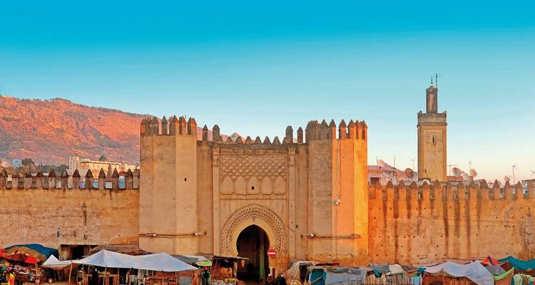 Bab Bou Jeloud, das kunstvolle blaue Tor von Fes, überragt geschäftige Marktstände im Morgengrauen
