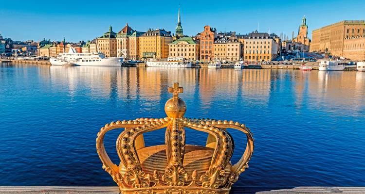 View of a crown sculpture above water with a city skyline.