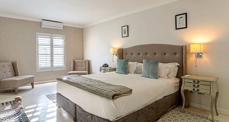 Elegant hotel room interior with a king-size bed, armchairs, and wall lamps.