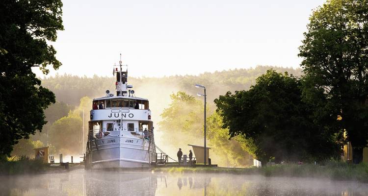 A boat named Juno docked on a misty canal.