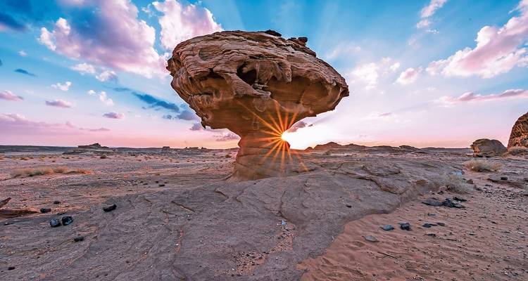 Unique rock formation with sunrays peeking through at sunset.