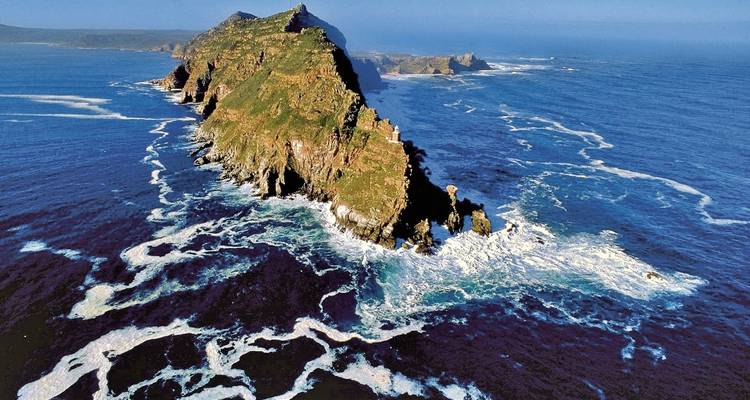 Luchtfoto van een ruige kustlijn met brekende golven.
