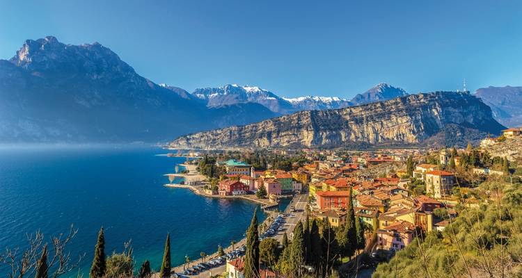 Vue panoramique d'une ville au bord d'un lac avec des montagnes en arrière-plan.