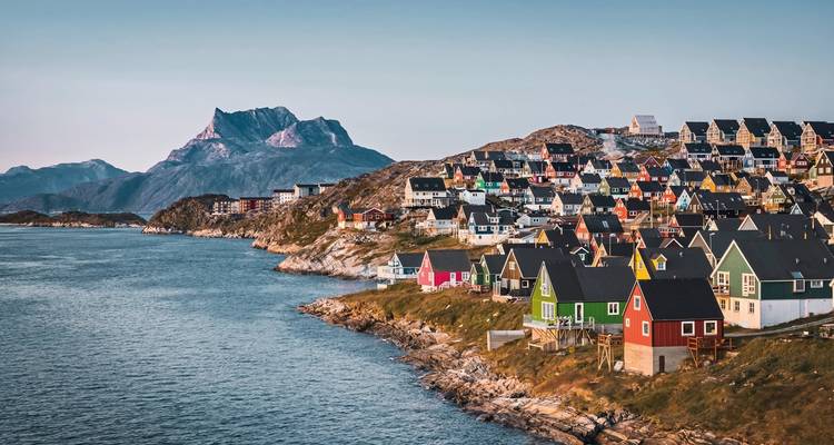 Colorful hillside houses overlooking a bay with mountains.