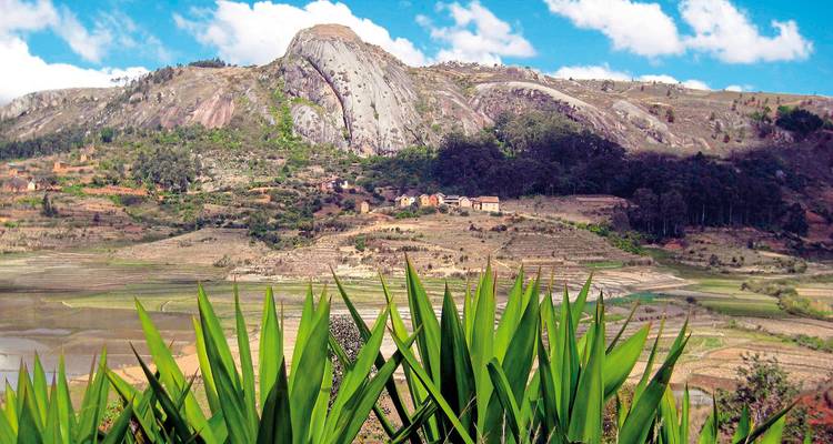Üppiges grünes Tal mit einem felsigen Hügel im Hintergrund.