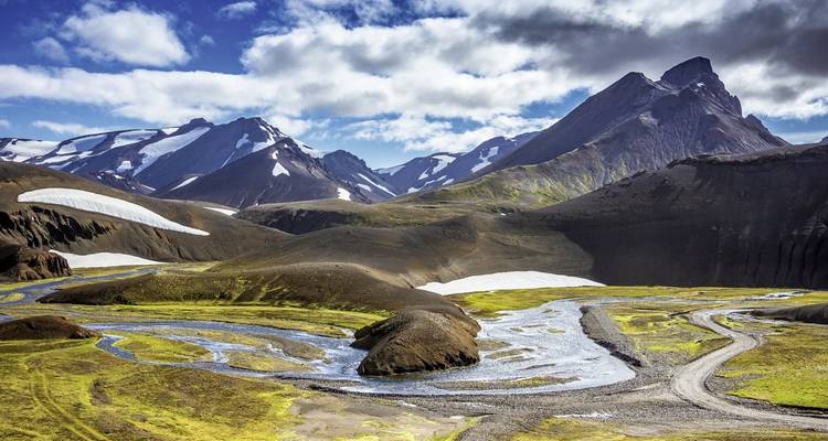 Bergige Landschaft mit Bächen und Schneeflecken.