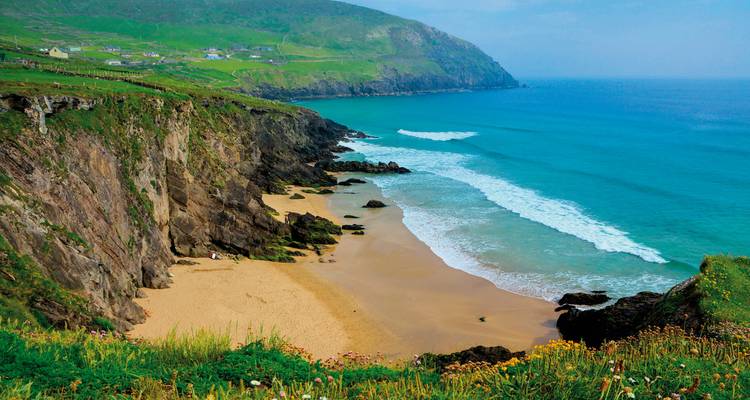 Abgelegener Sandstrand, umrahmt von rauen Klippen und türkisfarbenen Atlantikwellen in der Nähe von Dingle.