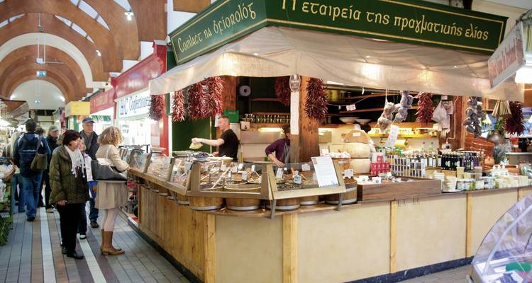 Overdekte marktkraam met mensen die eten en goederen bekijken.