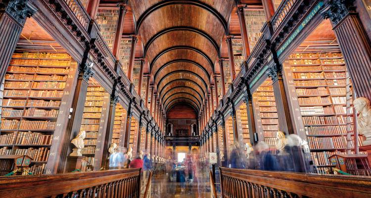 Interior of a grand library with numerous books and arches.