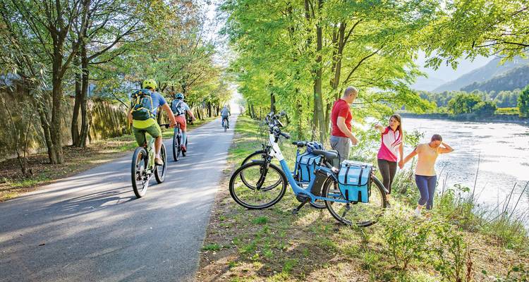 Famille avec vélos sur un sentier au bord de la rivière.