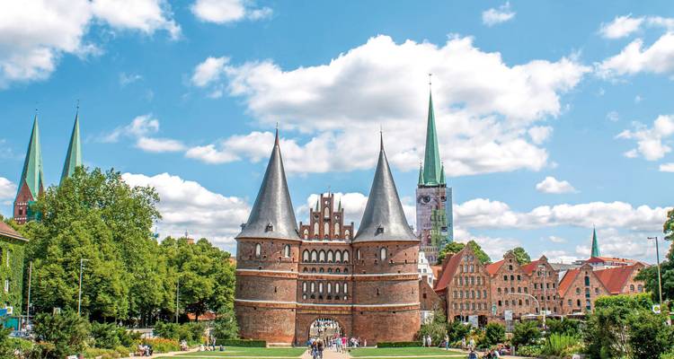 Historic city gate with crowded street and spires in the background.