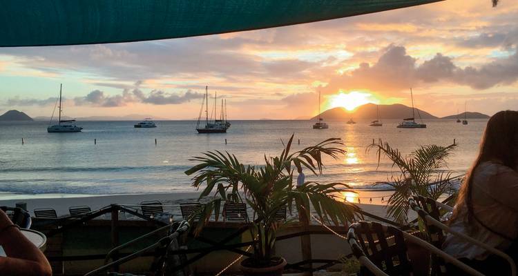 Coucher de soleil avec yachts et silhouettes de palmiers.