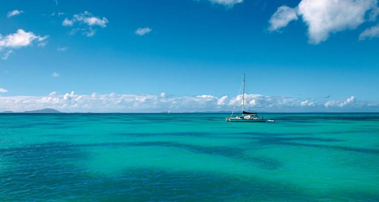 Mer ouverte avec un voilier sous un ciel dégagé.
