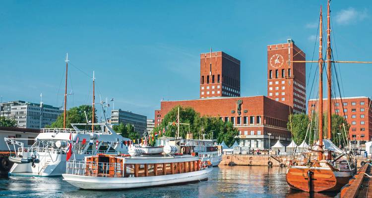 Boten aangemeerd in de haven van Oslo met het stadhuis op de achtergrond.