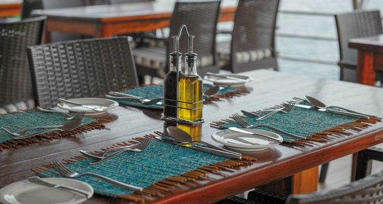 Eetopstelling op een schip met placemats en bestek op tafels.