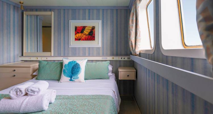 Gezellige hut met bed, ramen en decoratief kussen.