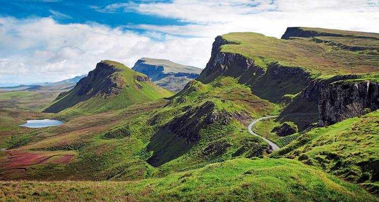 Dramatic landscape with green hills and a winding road.
