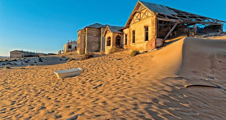 Verlaten gebouw gedeeltelijk begraven in zandduinen.