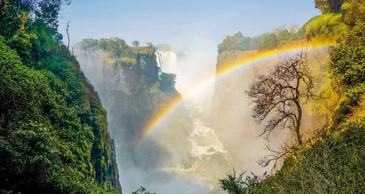 Majestic waterfall with a rainbow arching across the mist.