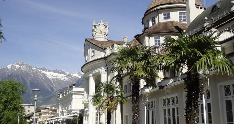 Elegante Gebäudefassade mit Palmen und Bergen.