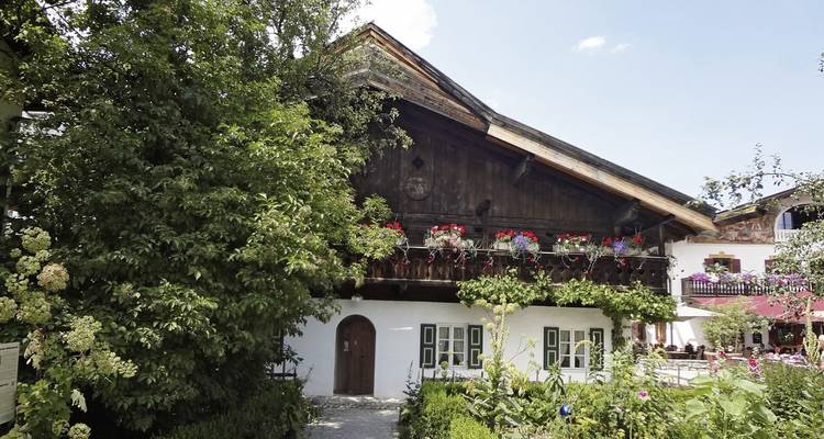 Traditionelles Gebäude mit Blumenkästen umgeben von Garten.
