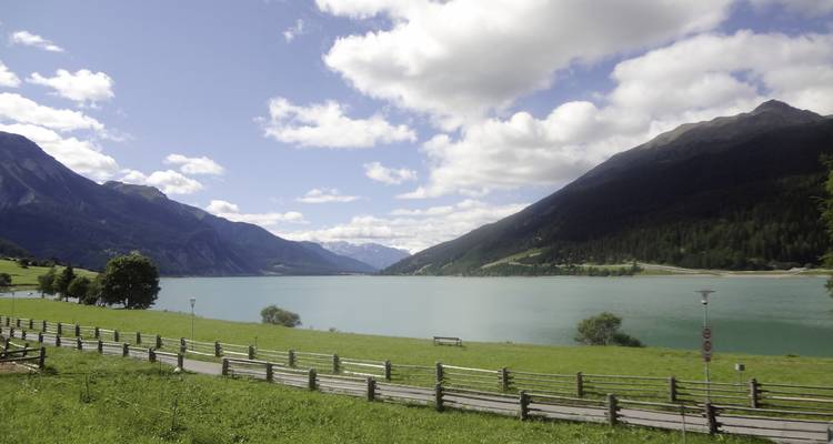 Seeblick mit grünen Feldern und Bergen.