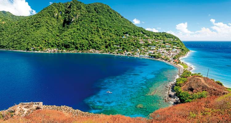 Vibrant bay with a lush mountainous coastline and colorful houses.