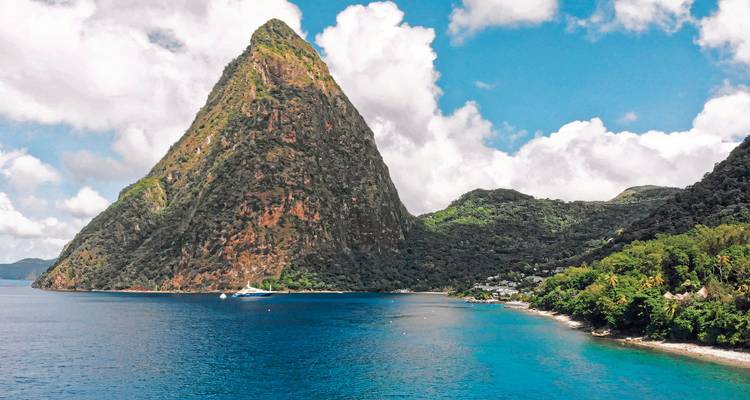 A large, pointed mountain and coastline with clear blue water.