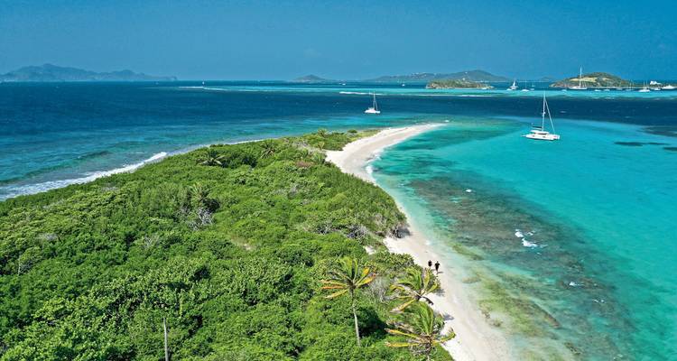 A long stretch of beach with a sandbar and distant islands.