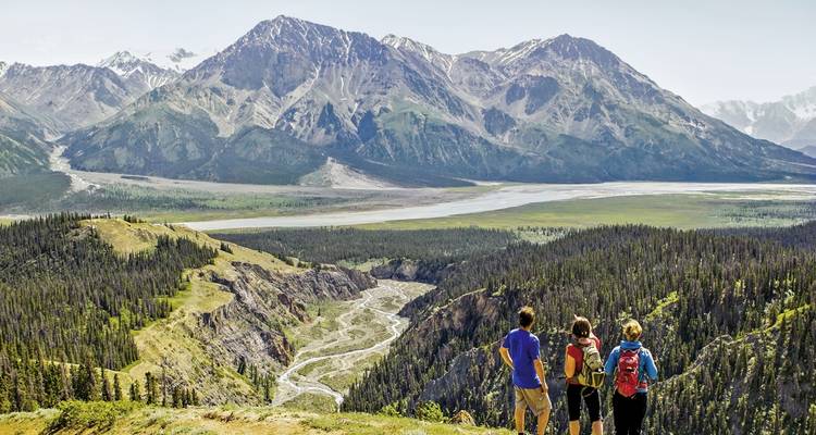 Trois personnes profitant d'une vue panoramique sur une vallée de montagne.
