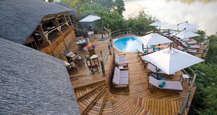 Holzdeck mit Pool und Sitzbereich mit Blick aufs Wasser.